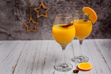 Two glasses with orange juice and cinnamon sticks on a dark gray background with stars