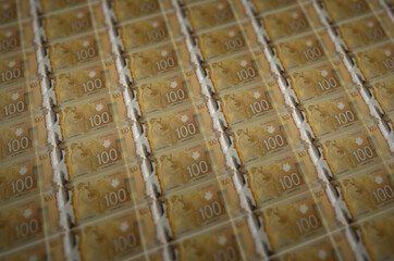 100 Canadian dollars bills printed in illegal money production conveyor. Collage of many fake...