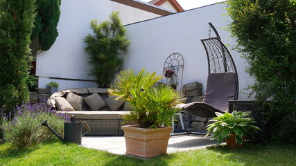 Gartenterrasse mit Loungegruppe und Hängesessel in einer Gartenecke mit Säulen-Faulbaum und...