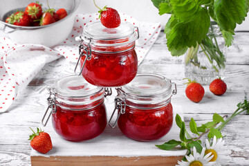 Strawberry jam in glass jar on the white wooden table