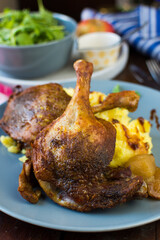 Festive roast duck on wooden table with oranges, hoi sin sauce and arugula leaves.