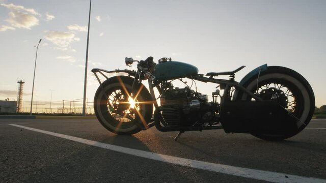 Close-up dolly shot of custom cafe racer motorcycle on sunset at street
