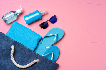 Beach essentials and blue beach bag on pink background