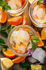 A refreshing summer drink with ice, mandarins and lemons in glasses top view