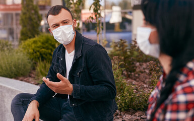 Fototapeta premium Young man in mask speaking with girlfriend