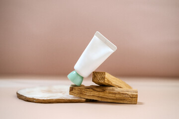 White cosmetic tube on light pastel peach color background. Natural minimalism, clean sustainable concept. Minimal styling scene, still life. Beauty blogging, skin care. Mock up, copy space 