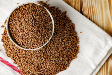 Bowl of raw uncooked buckwheat on wooden table