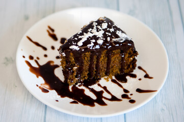 Piece of chocolate  cake with dark cream on white plate