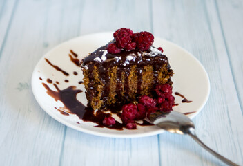 Piece of chocolate  cake with raspberries on white plate