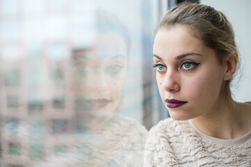 bellissimo ritratto di ragazza bionda con gli occhi verdi che sta vicino a una vetrata entro un...