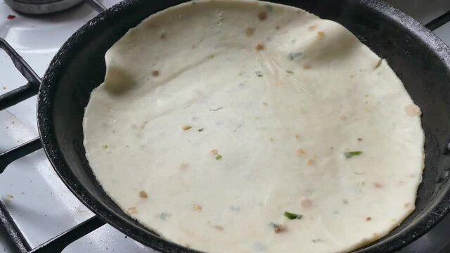 Placing traditional tasty raw Indian Partha hot pancake cooking on stove in pan