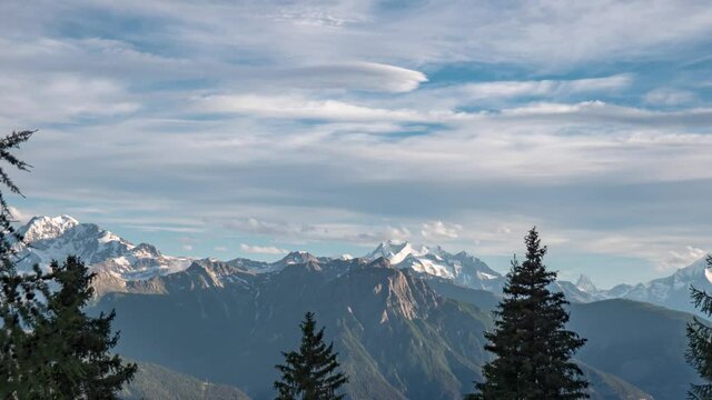Alpine sunset with glorious mountain peaks in distance and smooth clouds passing by, timelapse