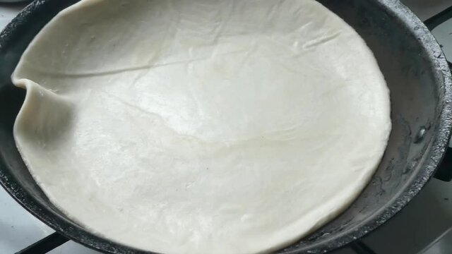 Indian Partha pancake placed in hot smoking stove pan to cook