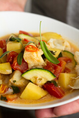 fish with vegetables and coconut sauce close-up.