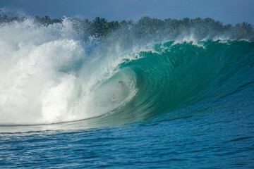 Surfer on perfect blue big tube wave, empty line up, perfect for surfing, clean water, Indian Ocean in Mentawai islands