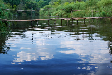 closeup small rural wooden bridge over the quiet summer river