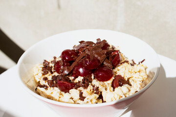 Bowl with oatmeal with cherry and chocolate on a table