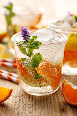 Cool soft drink with ice, mandarins and lemons in glasses close up view