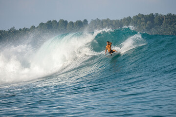 Obraz premium Surfer on perfect blue big tube wave, empty line up, perfect for surfing, clean water, Indian Ocean in Mentawai islands