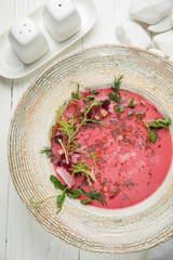 Cold tomato gazpacho soup. On a wooden, white table
