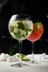 Assorted cold cocktails - mojito and raspberry. On a wooden, white table
