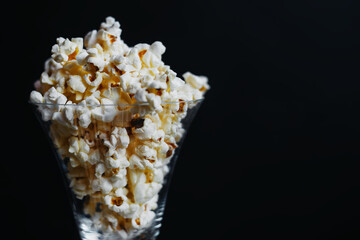 Salted popcorn in glass glasses on a black background.