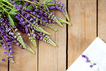 Bouquet of blue lupins and a book on a background of boards