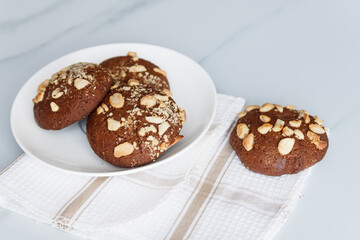 chocolate chip cookies with nuts and peanuts in a white tea plate on a table with a tea napkin