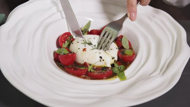 Salad with burrata mozzarella cheese, tomatoes and leafs of salad. Traditional italian caprese in high kitchen gourmet restaurant.