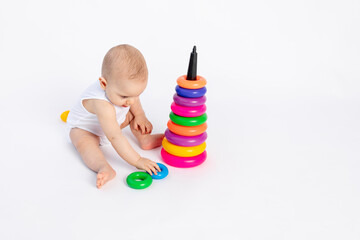 cute baby boy 8 months old playing with a pyramid on a white isolated background, place for text, early development of children