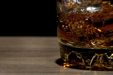 Glasses of whiskey with ice on wood