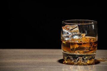 Glasses of whiskey with ice on wood