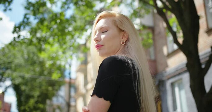 Portrait of mixed race blond woman looking confident. Wearing black dress and sunglasses. Grey urban city background.