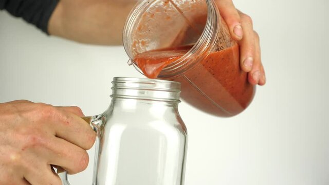 A rich red healthy smoothie is poured into a trendy kilner jar with handle. Superfood juice drink