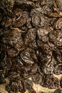 Dried prunes in bulk on burlap with a rough texture. Close up.