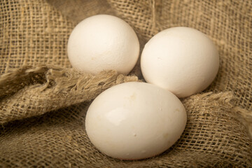 White chicken eggs on a background of homespun fabric with a rough texture. Close up.