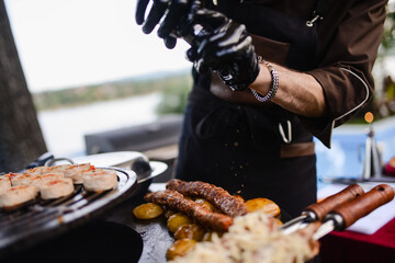 The chef puts the spice on the minced kebab meat while grilling. Picnic in the yard