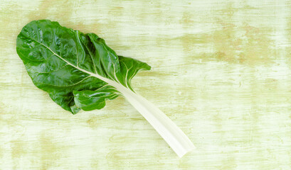 Chard leaf on a green wooden background. Concept of vegetables. Copy space.
