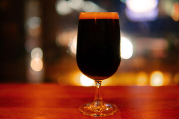 Stout beer or dark beer in a glass on the wooden table and bokeh background.  Copy Space for text.