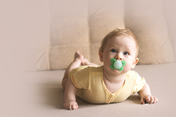 baby lying on the sofa with his pacifier. Soft focus, copy space.