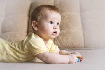 Naklejka premium Baby lying on his stomach on a bed on a beige background. Soft focus, copy space.