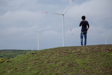 Indian man standing in front of the windmills at Wankaner, Gujarat, India