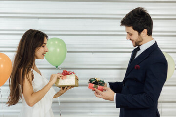 Young Caucasian couple celebrating new year together, exchanging gifts to each other.