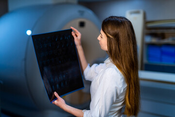 Competent doctor reading x-ray near the magnetic resonance imaging machine.