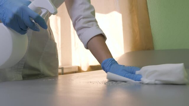 Process of cleaning and disinfecting the patient's couch. Doctor in blue gloves applies cleaning agent to the surface and cleans it with a cloth. Close up.