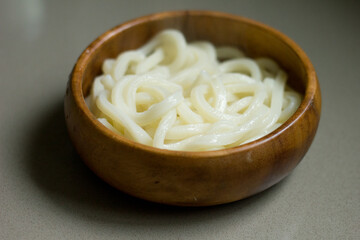Steaming bowl of Japanese udon noodles in a round wooden bowl.