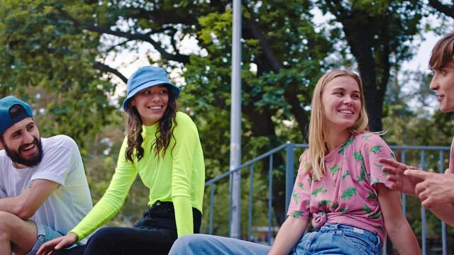 Beautiful ladies with a perfect smile and attractive guys have a discussing in a modern skate park they socializing and spending a good time together wearing stylish outfits