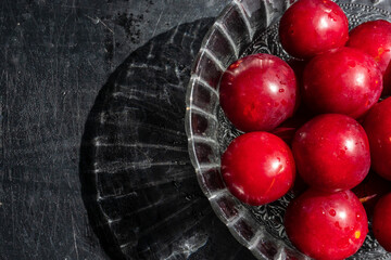 red plums with a black wooden background 