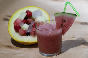 Watermelon smoothie with ice in a glass cup and a slice of watermelon on top. Summer drink.