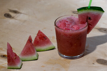 Watermelon smoothie with ice in a glass cup and a slice of watermelon on top. Summer drink.